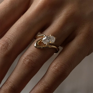 Detail eines luxuriösen Goldrings mit ovalem Zirkonia und gewelltem Design am Finger