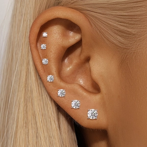 Close-up of seven graduated moissanite stud earrings with classic four-prong silver setting