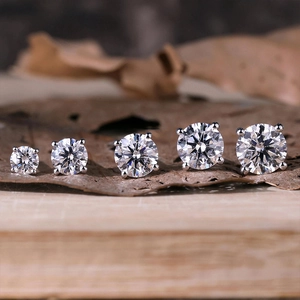 Macro view of five sizes of S925 sterling silver moissanite stud earrings on wood