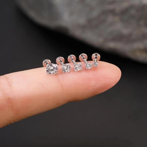 Macro view of five S925 silver moissanite labret studs in varying sizes on a fingertip