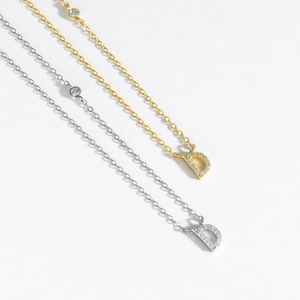 Close-up of gold and silver S925 sterling silver necklaces with iced out D letter pendants