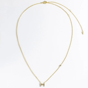 Detail of gold letter M pendant with zircon stones and elegant cable chain necklace