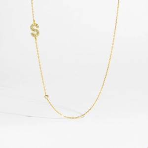 Detail of gold letter S pendant with pavé zircons and a small round bezel-set crystal