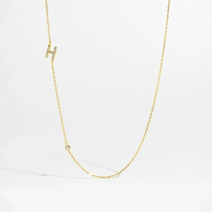 Macro detail of gold S925 silver necklace with zircon and letter H pendant