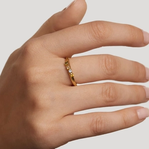 Minimalist gold ring with colorful zircon stones on female hand with soft lighting