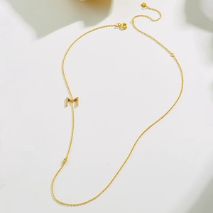 Detailed macro of gold plated S925 silver necklace with M pendant and zircon stones