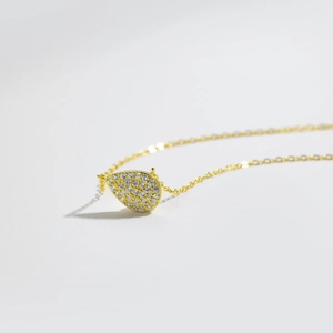 Macro shot of gold pear-shaped pendant with micropave cubic zirconia on delicate link chain