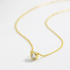 Minimalist S925 silver necklace with a bezel-set round white stone pendant in gold finish