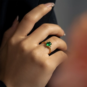 Bague élégante en argent S925 doré avec pierre verte ovale et diamants portée par modèle