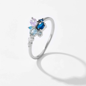 Detalle de anillo de plata con piedras azules y rosas en un engaste de racimo