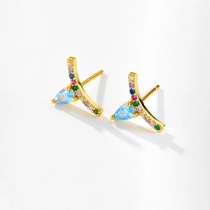 Detalle macro de pendientes chapados en oro con circonitas de colores y piedra de pera azul