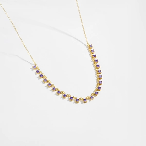 Close-up of gold chain necklace with round purple stones in a four-prong setting