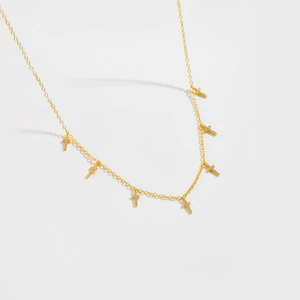 Vue détaillée des pendentifs croix dorés avec strass blancs sur une chaîne fine