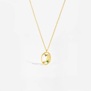Detail of gold oval pendant with colorful gemstones and letter J on a gold chain