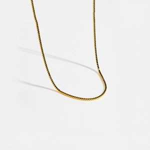 Détail d'un collier tennis doré minimaliste serti de pierres de zircon noir brillant