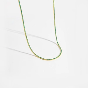 Vue détaillée du collier tennis doré avec pavage de cristaux de couleur sarcelle