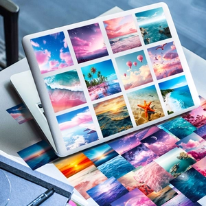 Detail of scenery stickers with sunset and beach views on a silver laptop surface