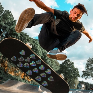 Close-up of holographic heart stickers with iridescent effects on a black skateboard