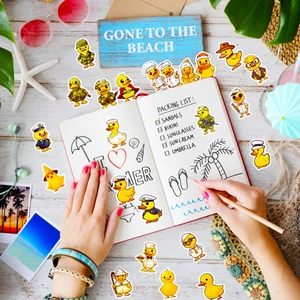 Flat lay of cute yellow duck stickers with summer travel props on white wood surface