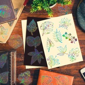 Autocollants de feuilles laser holographiques décorant un carnet sur une table en bois