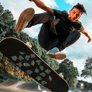 Autocollants feuilles laser sur un skateboard lors d'un saut dans un skatepark