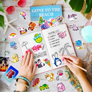 Flat lay of colorful cartoon stickers on a notebook with summer vacation accessories