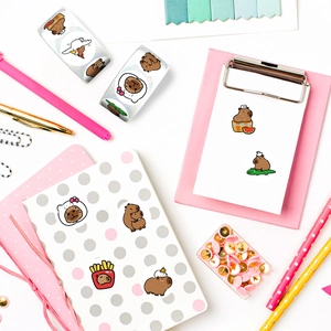Close-up of cute cartoon Capybara reward stickers on a pink notebook with stationery