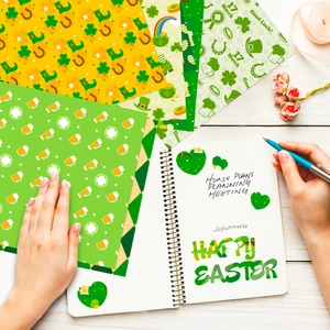 Flat lay of St. Patrick's Day craft paper with shamrocks and beer patterns for DIY
