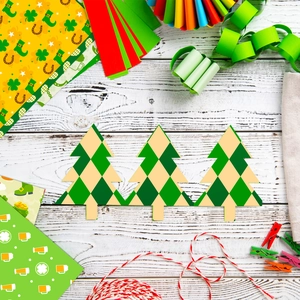 Flat lay of St. Patrick's Day DIY paper trees with green argyle pattern on white wood