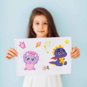 Close-up of a girl holding DIY cartoon dinosaur stickers with colorful cute face patterns