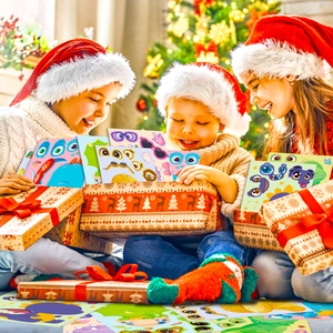 Children in Santa hats opening gift boxes filled with colorful DIY monster stickers