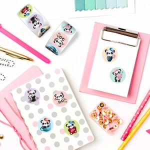 Detailopname van ronde panda-stickers met hartjes en bloemen op een wit notitieboek