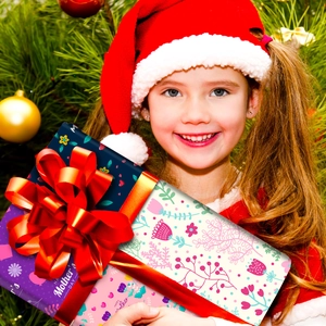 Detail of Mother's Day gift box with a large red bow and floral patterns held by a child