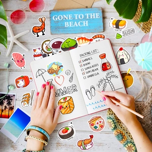 Close-up of cute sushi stickers being applied to a journal with summer beach decor