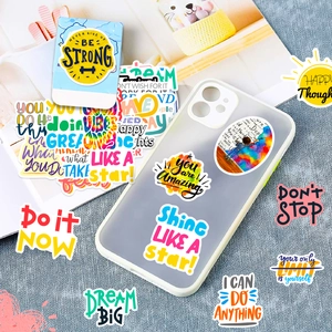Gros plan de stickers de motivation avec phrases BE STRONG et DREAM BIG sur fond bleu