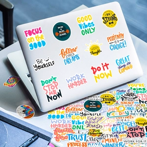 Détail d'autocollants colorés avec citations anglaises motivantes sur un ordinateur portable