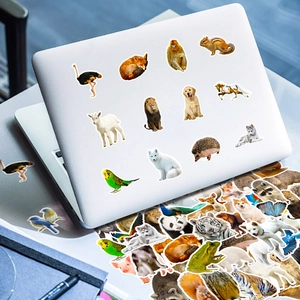 Close-up of realistic animal stickers applied on a silver laptop and layered decorations