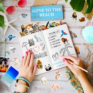 Detail of cute animal watercolor stickers on a notebook with beach style props