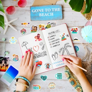 Flat lay of colorful Happy Father's Day stickers on a white desk with summer props