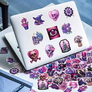 Gothic purple stickers displayed on a silver laptop featuring skulls and dark magic motifs