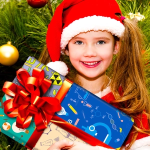 Girl holding gift wrapped in science-themed paper with DNA and flask patterns