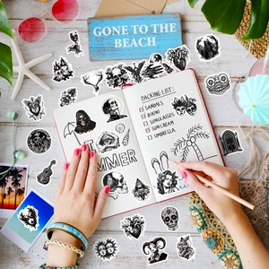 Close-up of black and white gothic punk stickers with eyes and skulls on a notebook