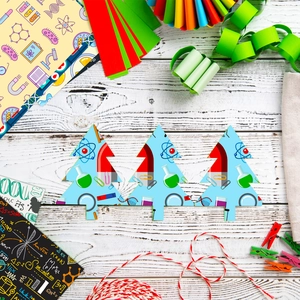 Flat lay of science-themed Christmas tree paper crafts on a white vintage wood background