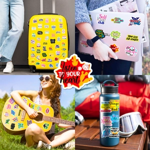 Close-up of motivational stickers with English phrases on a laptop and phone