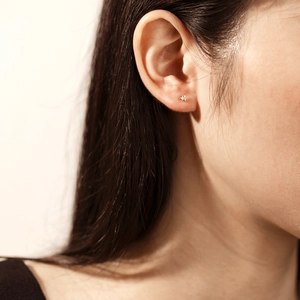Gros plan sur un clou d'oreille minimaliste en or à trois perles porté sur le lobe