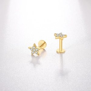 Gros plan de boucles d'oreilles étoiles dorées serties de zircons sur cuir blanc