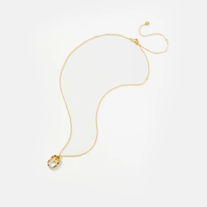 Macro detail of 925 silver gold necklace with colorful zircon-encrusted initial M pendant
