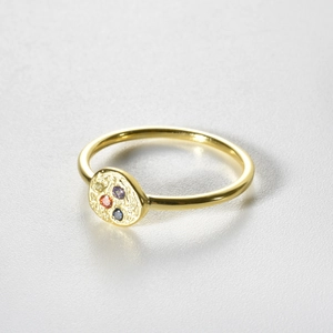 Close-up of golden hammered ring featuring four colorful round zircon gemstone settings
