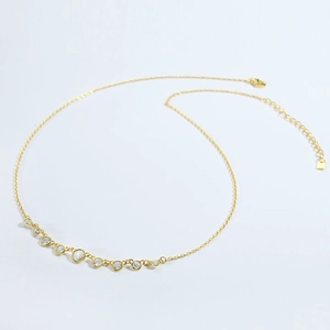 Detail view of gold necklace with eleven bezel-set round cubic zirconia and lobster clasp