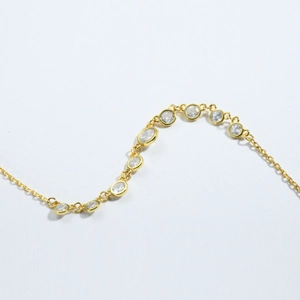 Close-up of polished gold S925 silver necklace with round and oval bezel-set crystals